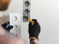 Electrician installs decorative frame on electric and TV sockets.