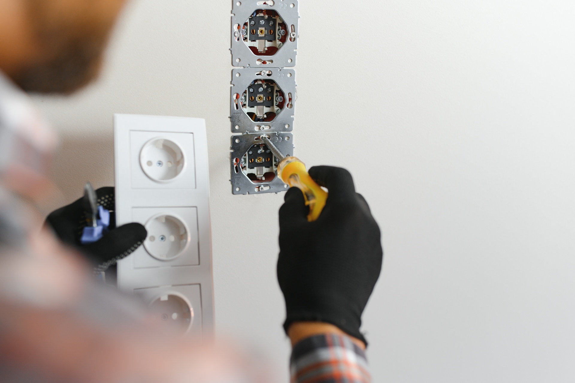 Electrician installs decorative frame on electric and TV sockets.